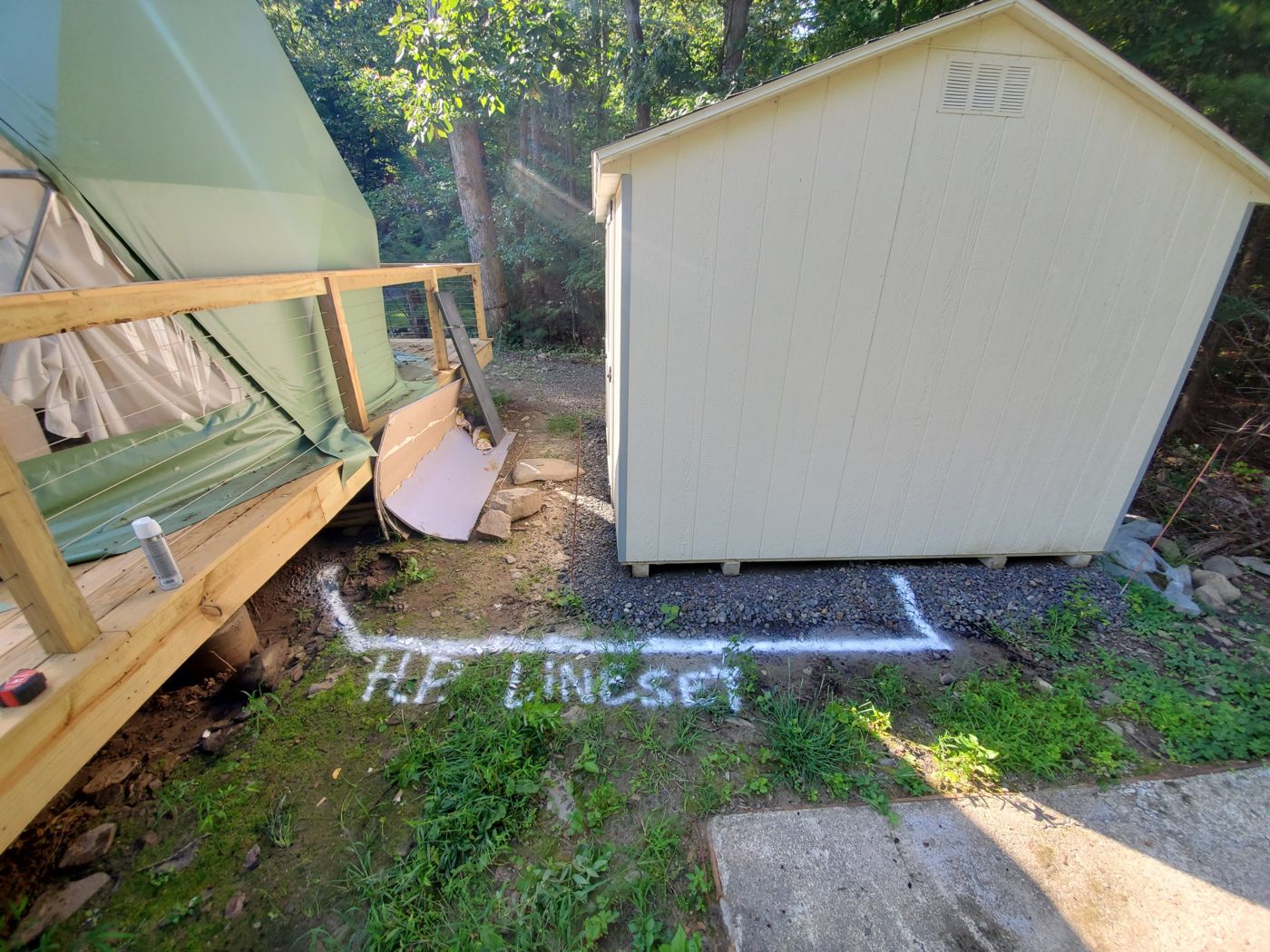 Ground marked with white paint reading HP line set, showing the trench route from a storage shed to the dome's deck