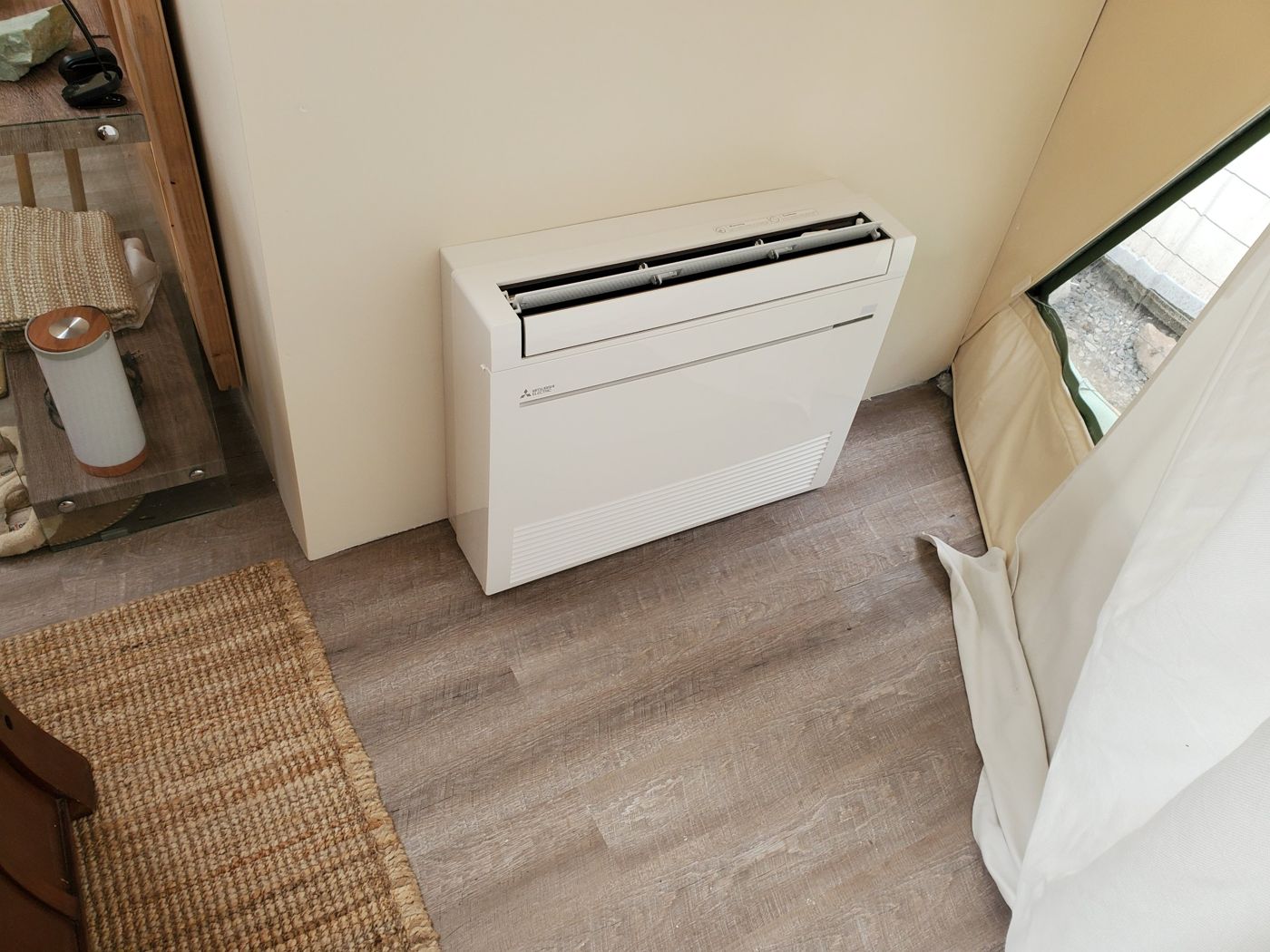 Mitsubishi Electric floor-mounted console heat pump on a wood-look floor beside the dome's fabric wall