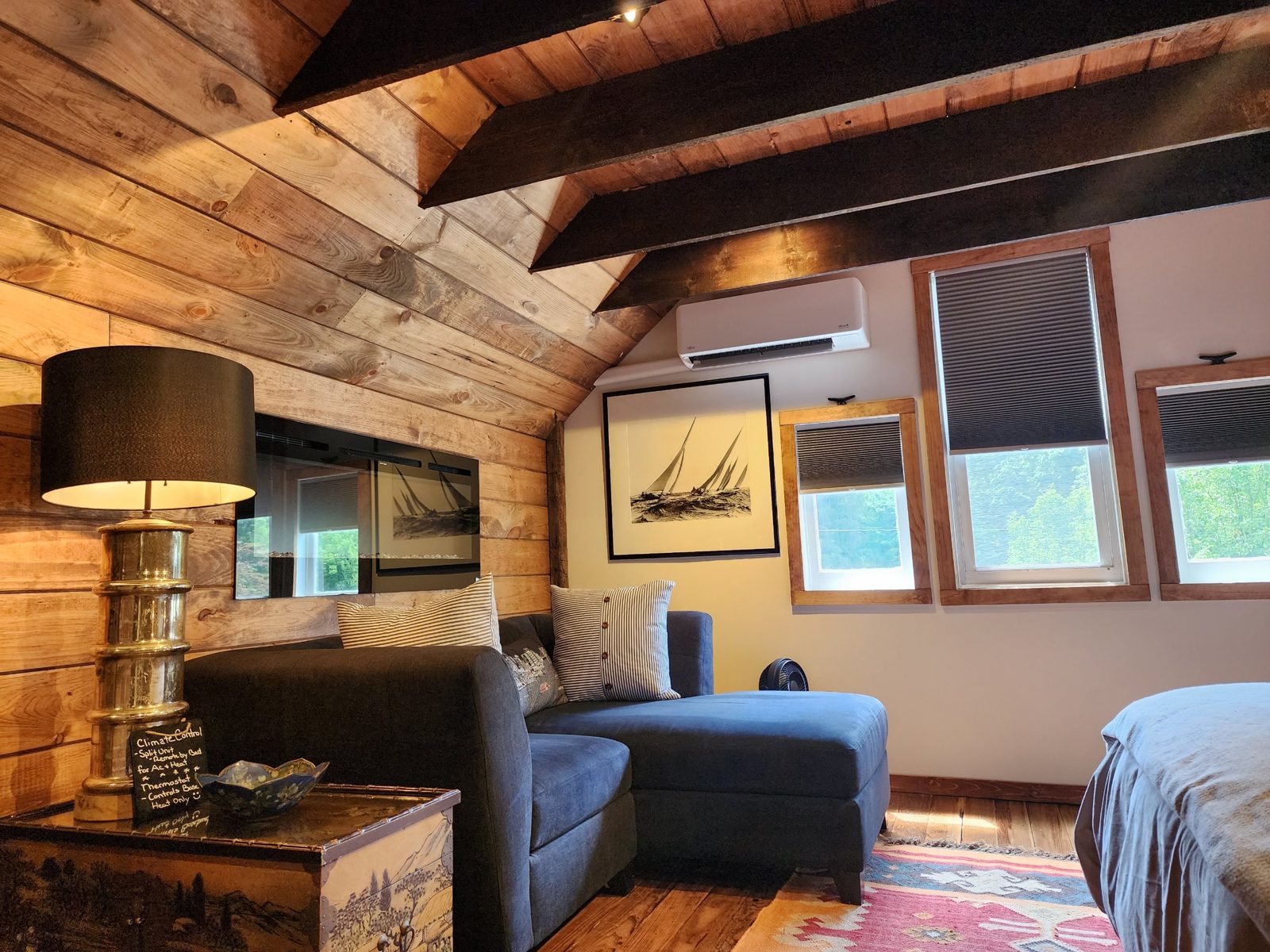 Fujitsu ductless wall unit installed high on the wall of a finished attic bedroom with exposed beams